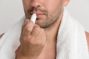 Hombre aplicándose protector labial. 